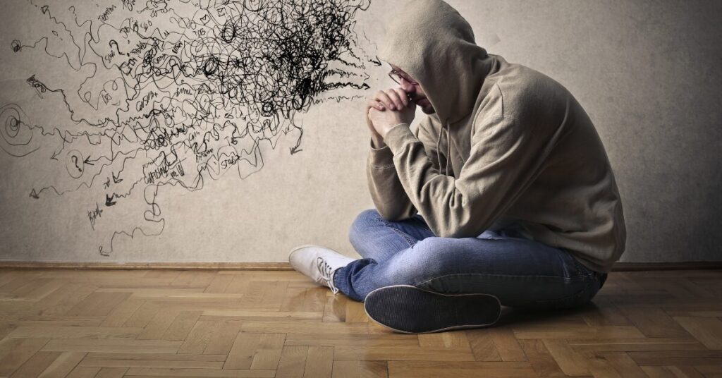 man head in hands seemingly thinking negative thoughts