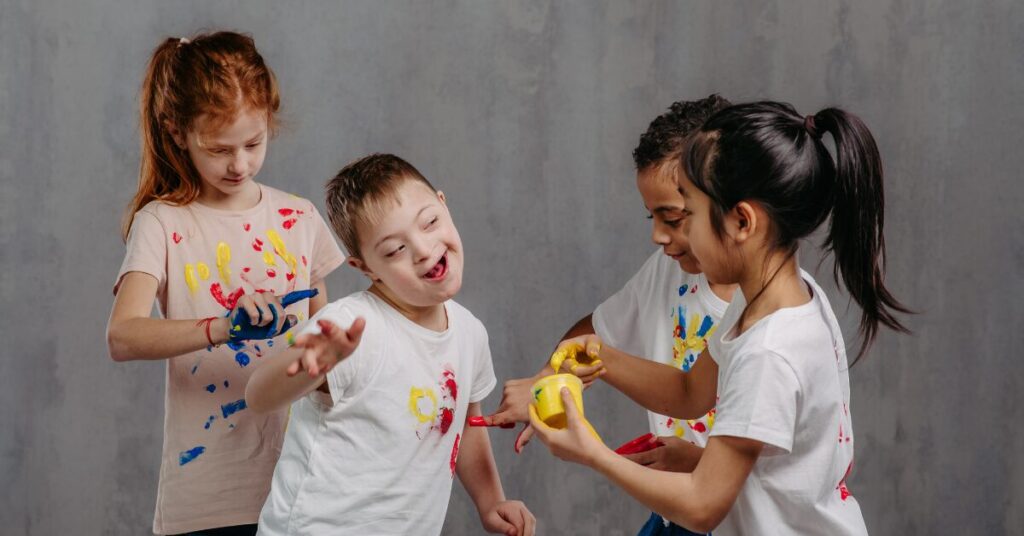 trauma reaction two four young children one with special needs finger painting on each other's t-shirts to signify the diversity of reactions from trauma